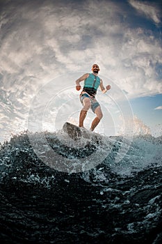 athletic man wavesurfer actively balancing on wakeboard along the river wave