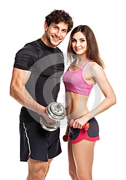 Athletic man and woman with dumbbells on the white