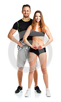 Athletic man and woman with dumbbells on the white