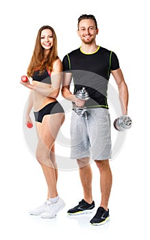 Athletic man and woman with dumbbells on the white