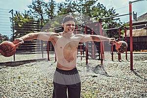 Athletic man working out with a kettlebell at street gym yard. Strength and motivation.