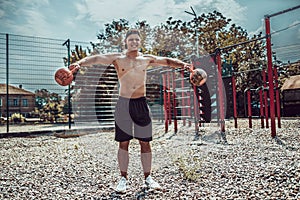 Athletic man working out with a kettlebell at street gym yard. Strength and motivation.