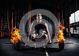 Athletic man works out at the gym with a fiery barbell