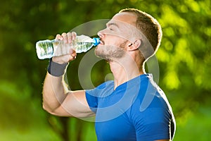 Athletic mature man drinking water from a bottle