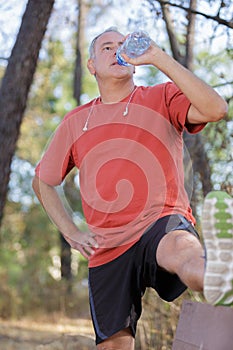 Athletic mature man drinking water from bottle