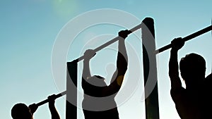 Athletic men doing pull-ups on chin-up bars, preparing for sports competition