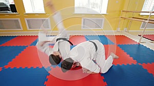 Athletic men engaged in martial art of aikido. A man grabs his opponent and throws him on the floor