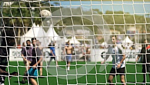 Athletic men playing soccer at stadium, view through net, healthy lifestyle