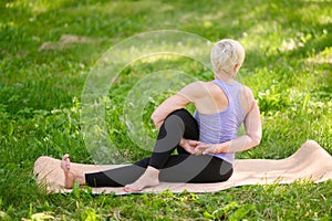 Athletic middle-aged woman doing yoga outdoors in a city park.Meditation concept.Ardha Matsyendrasana