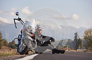 Athletic motorcyclist in black leather clothing sitting at modern powerful shiny motorbike.