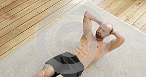 Athletic muscular man doing abs exercises crunches at home on floor, top view.