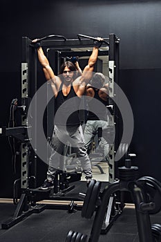 Athletic muscular man doing pull-ups in a gym