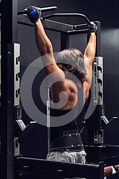 Athletic muscular man doing pull-ups in a gym