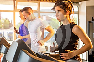 Athletic people having a sports training on treadmills at gym.