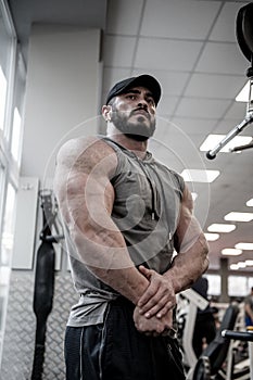 Athletic physique concept of strong young man with beard in sport gym