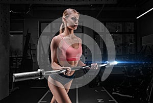 Athletic physique woman posing in the gym with a barbell in her hands. The concept of sports, fitness, healthy lifestyle