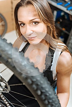 Athletic pleasant craftswoman repairing bicycle in the garage