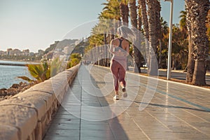 Athletic pretty woman actively running by the waterfront