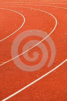 Athletic red running tracks whit white lines and some leaves on it