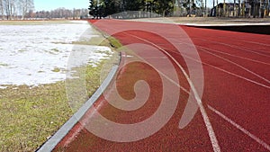 Athletic Running track in old stadium with snow in early spring, aerial