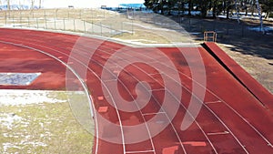 Athletic Running track in stadium with snow in early spring, aerial