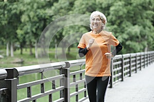 Athletic Senior woman running outdoor jogging in park.