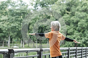 Athletic Senior woman stretching arms in park.