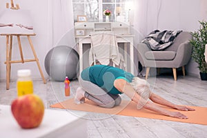 Athletic senior woman stretching on yoga mat