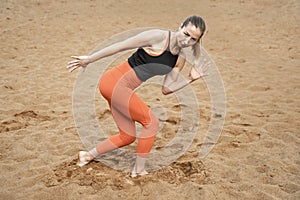 Athletic sexy middle-aged woman, doing fitness barefoot on the sand