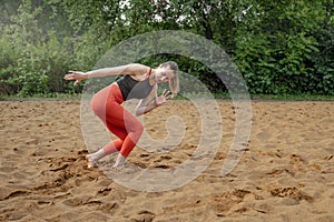 Athletic sexy middle-aged woman, doing fitness barefoot on the sand