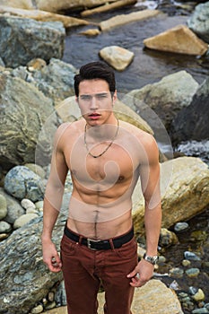 Athletic shirtless young man outdoor at river or water stream