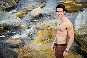 Athletic shirtless young man outdoor at river or water stream