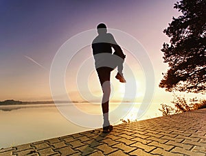 Athletic sport man stretching leg muscles before run