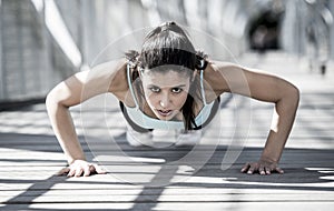 Athletic sport woman doing push up before running in urban training workout