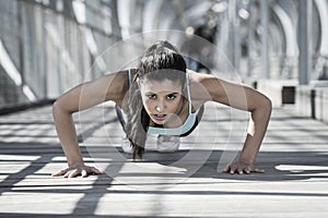 Athletic sport woman doing push up before running in urban training workout