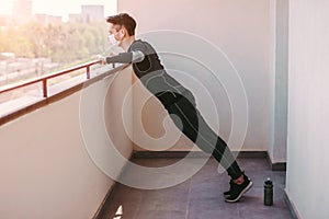 Athletic sports man doing push ups exercise on balcony at home