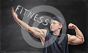 Athletic sportsman standing on the background with word 'fitness'.