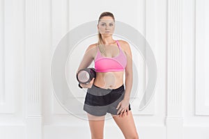 Athletic sporty beautiful blonde woman standing, holding foam roll and looking at camera.