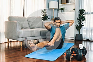 Athletic and sporty man doing crunch on fitness mat at gaiety home.