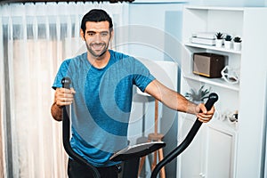 Athletic and sporty man running on elliptical running machine at gaiety home.