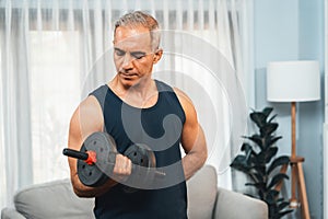 Athletic and sporty senior man lifting dumbbell at home. Clout