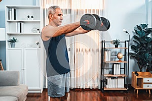 Athletic and sporty senior man lifting dumbbell at home. Clout