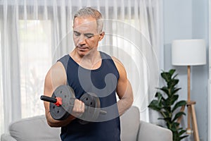 Athletic and sporty senior man lifting dumbbell at home. Clout