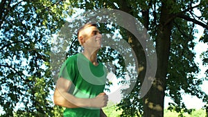 Athletic sporty young man jogging in public park