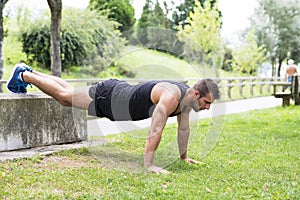 Athletic strong man doing pushups, outdoor.