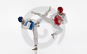 Athletic, strong young men, taekwondo athletes in motion, fighting, training isolated over white background. Martial