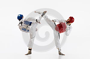 Athletic, strong young men, taekwondo athletes in motion, fighting, training  over white background. Martial