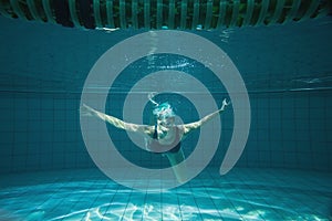 Athletic swimmer smiling at camera underwater