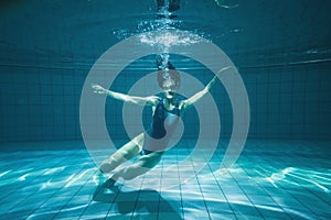 Athletic swimmer smiling at camera underwater