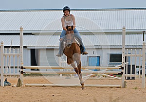 Athletic teen girl jumping a horse over rails.